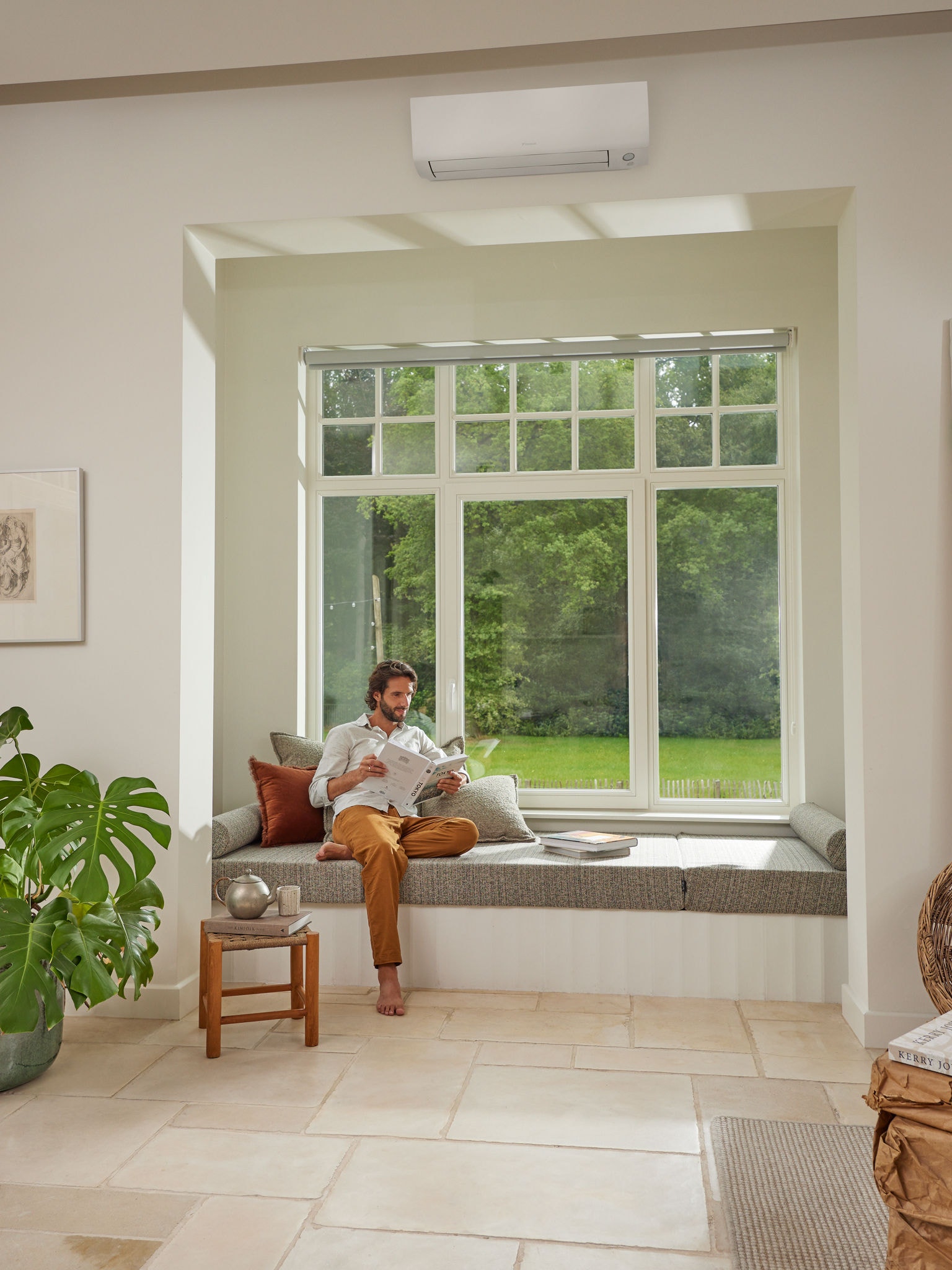 Hombre leyendo una revista en su sala de estar, disfrutando de un aire sano gracias al equipo de aerotermia aire-aire de Daikin que proporciona aire limpio