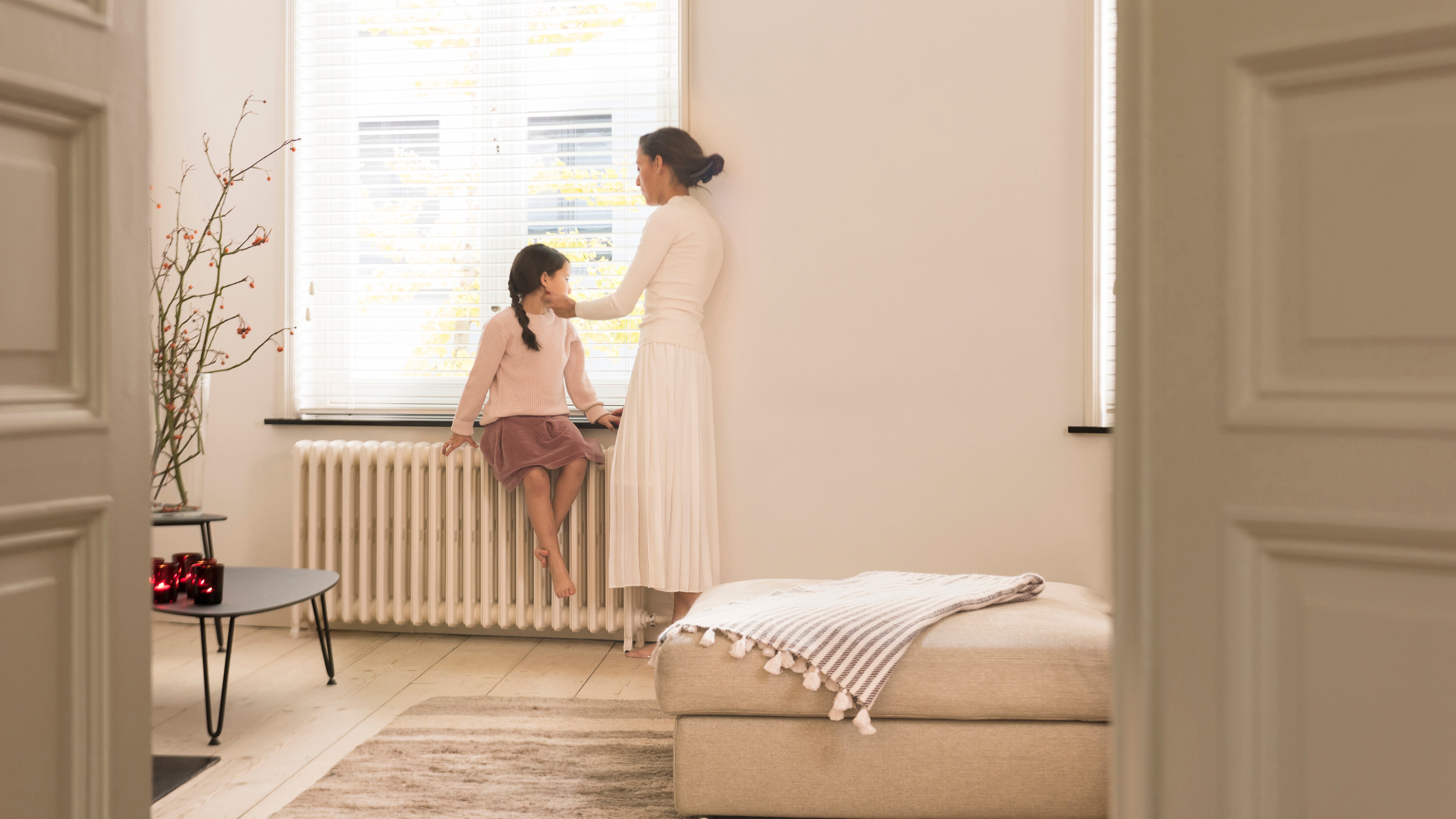 Mother and daughter looking out of the window from their perfectly heated living room