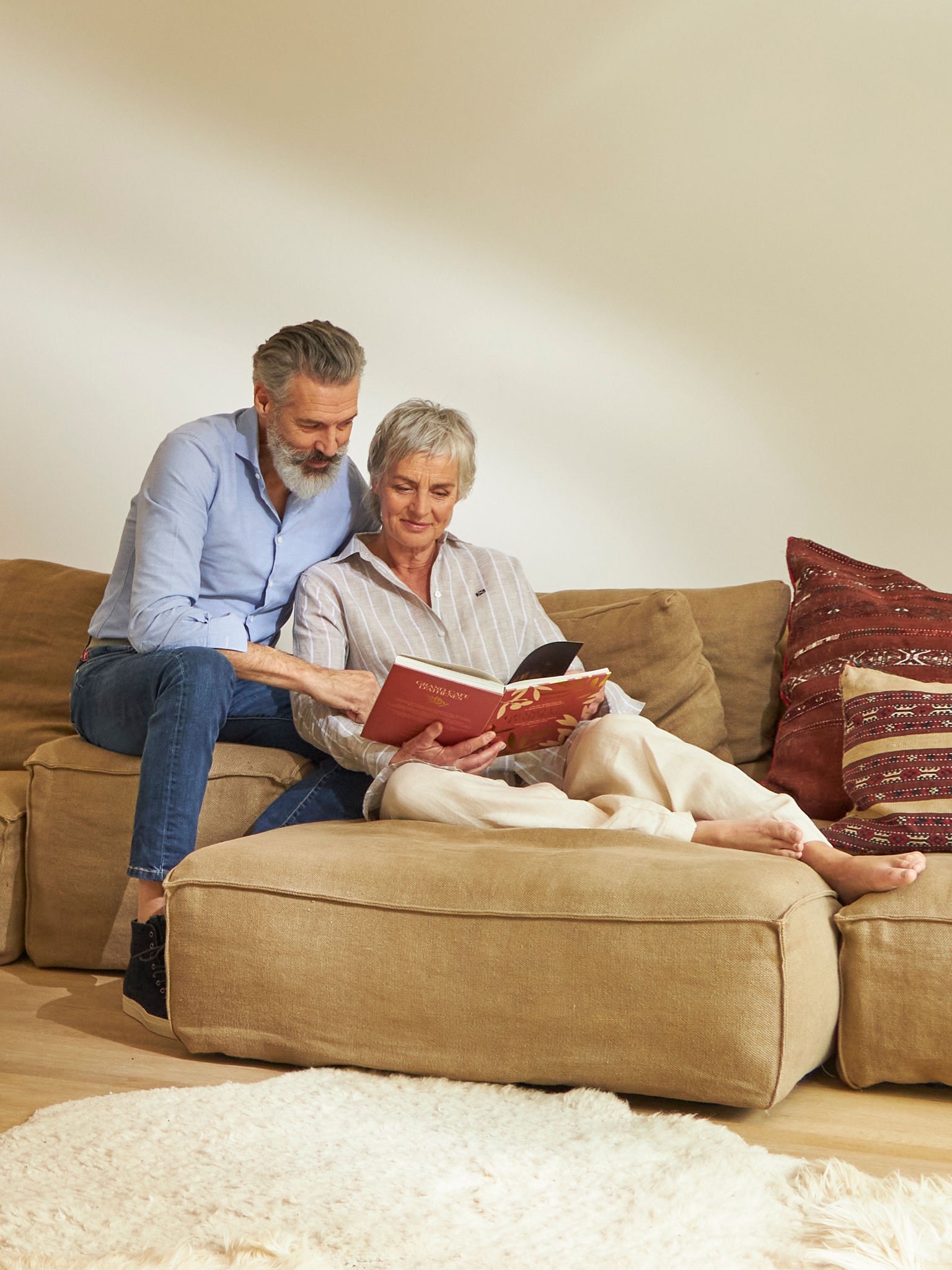 Middle-aged couple reading and relaxing on their couch while enjoying good indoor air quality