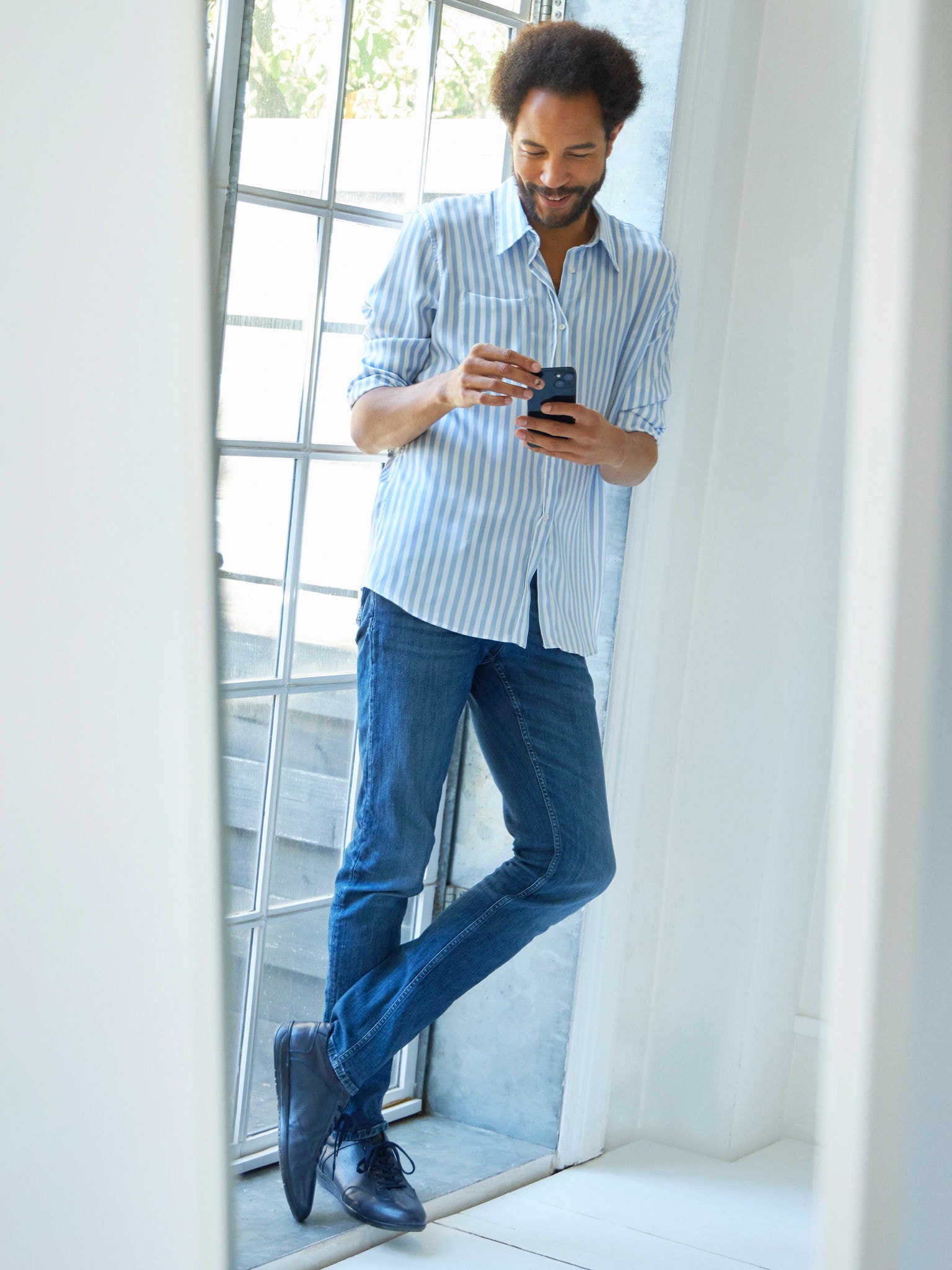 Hombre de pie cerca de una ventana viendo unidades aires acondicionados en el Virtual Experience Centre en tu smartphone