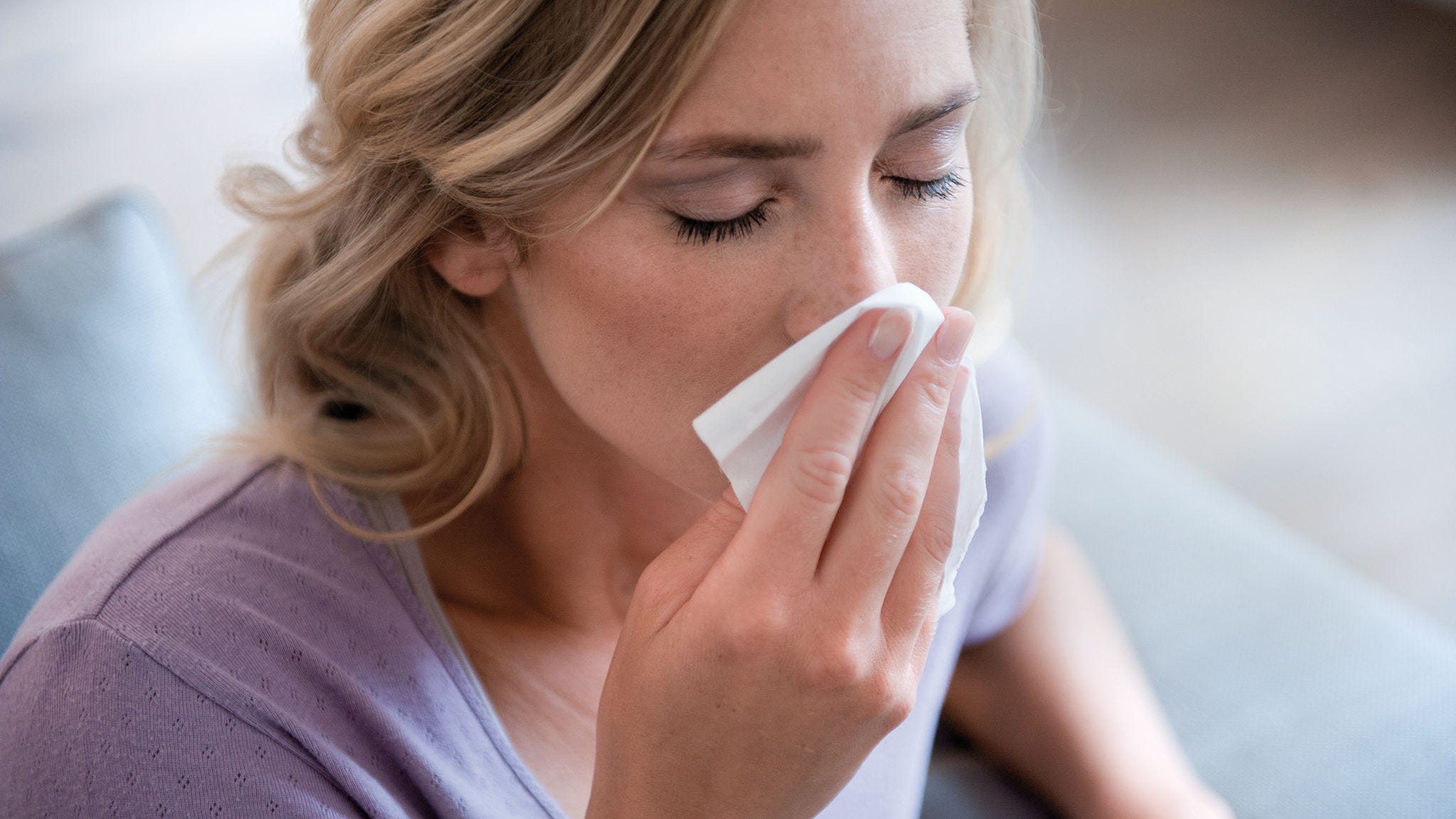 Woman blowing her nose due to pollen allergy