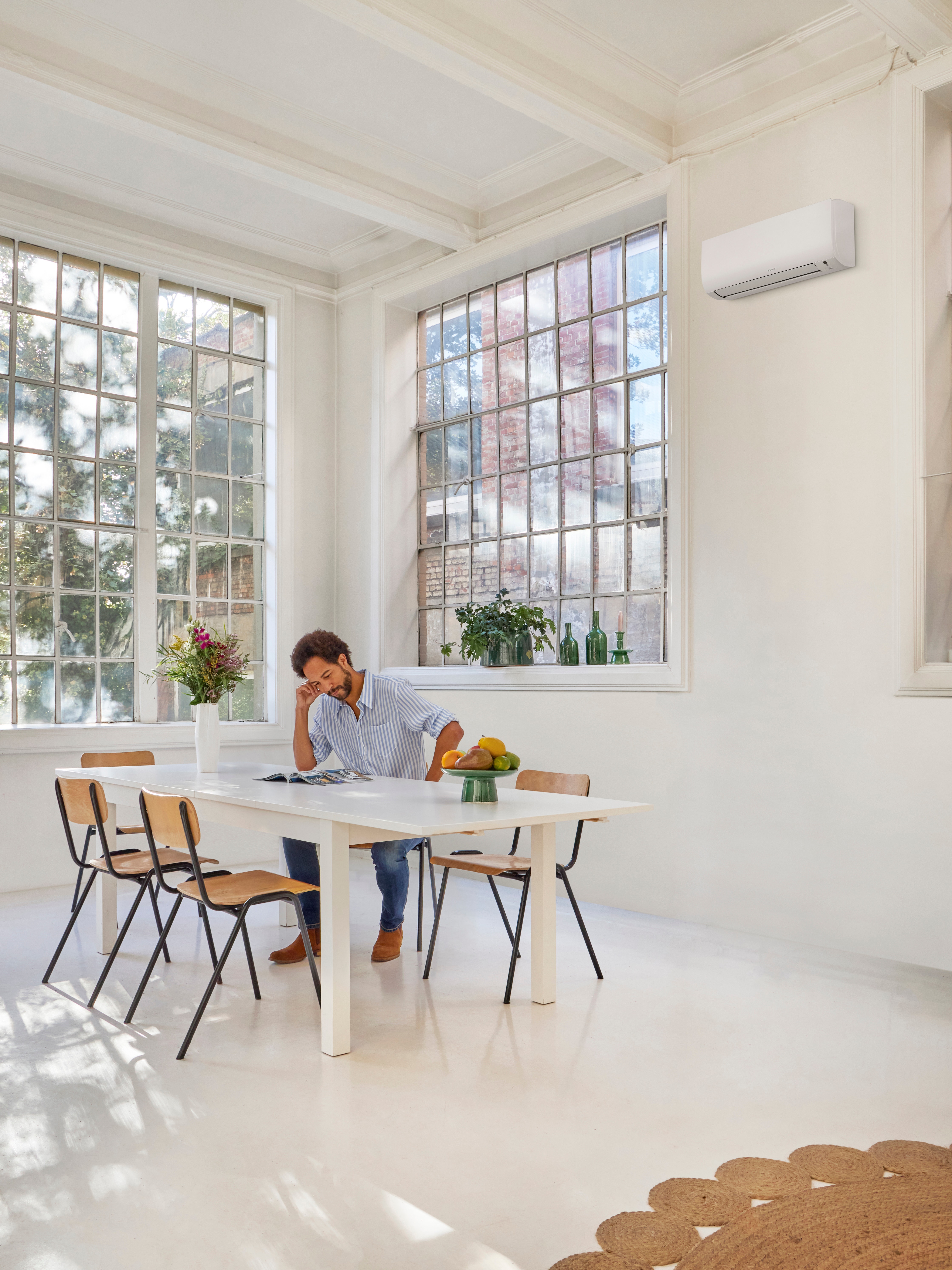 Un hombre está leyendo en la mesa mientras disfruta de la temperatura perfecta en el interior de su casa