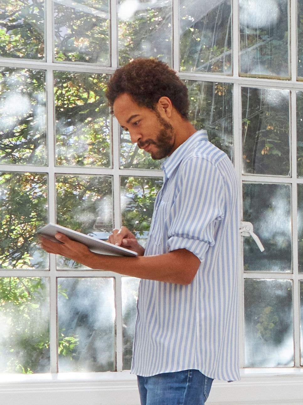 Hombre de pie cerca de una ventana viendo unidades aires acondicionados en el Virtual Experience Centre en su tablet.