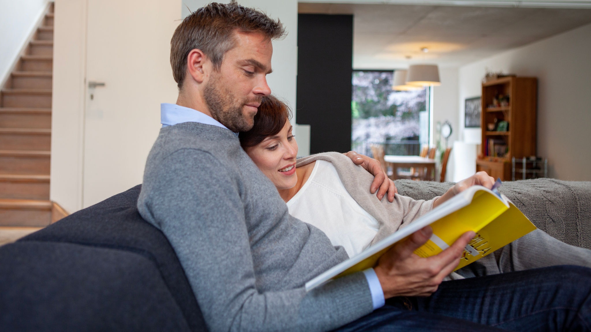 Pareja leyendo relajada en casa gracias a la temperatura perfecta que ofrece el aire acondicionado Stylish