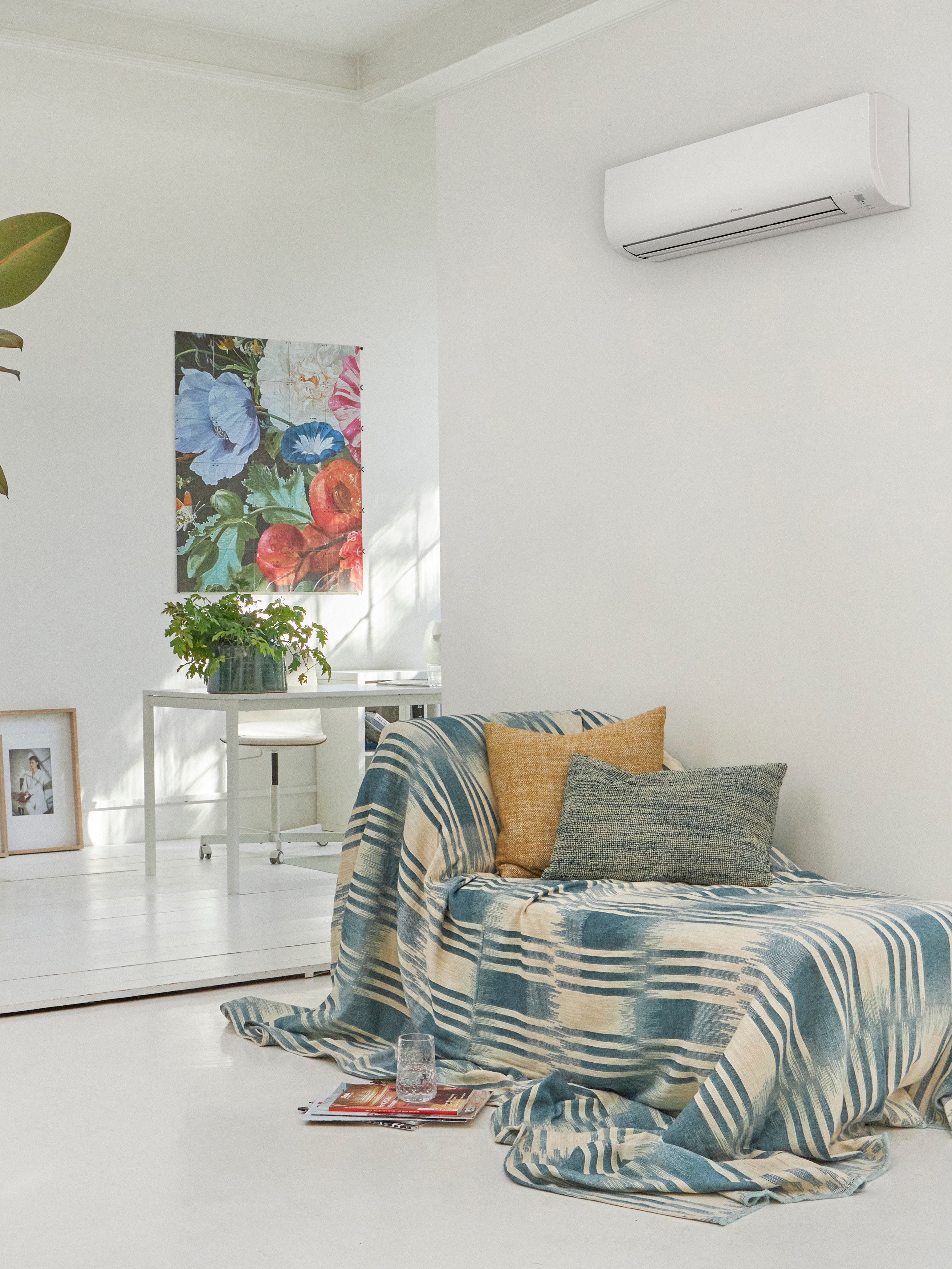 Sala de estar blanca con un sofá y un climatizador de pared encima.