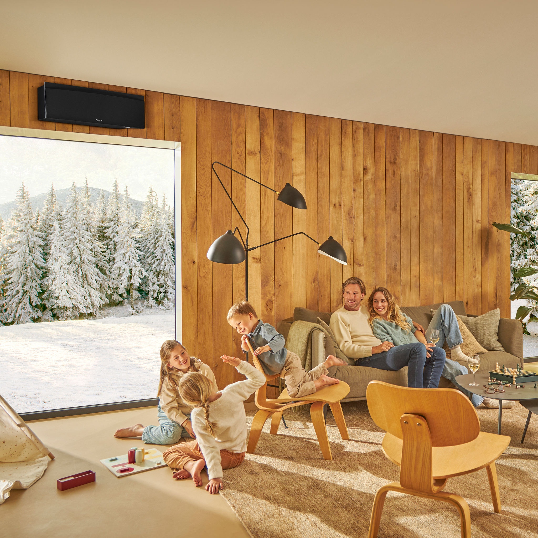 Familia disfrutando de un salón cálido y acogedor con un paisaje invernal en el exterior, mostrando la eficacia de nuestras soluciones de calefacción, aire acondicionado y ventilación para crear un ambiente interior confortable durante todo el año