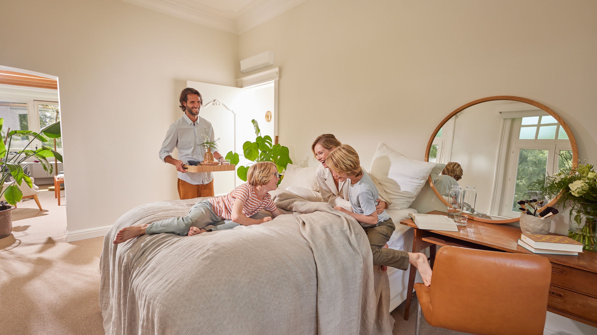 Una familia disfrutando de un momento acogedor en un dormitorio con un equipo de aerotermia híbrido instalado en la pared