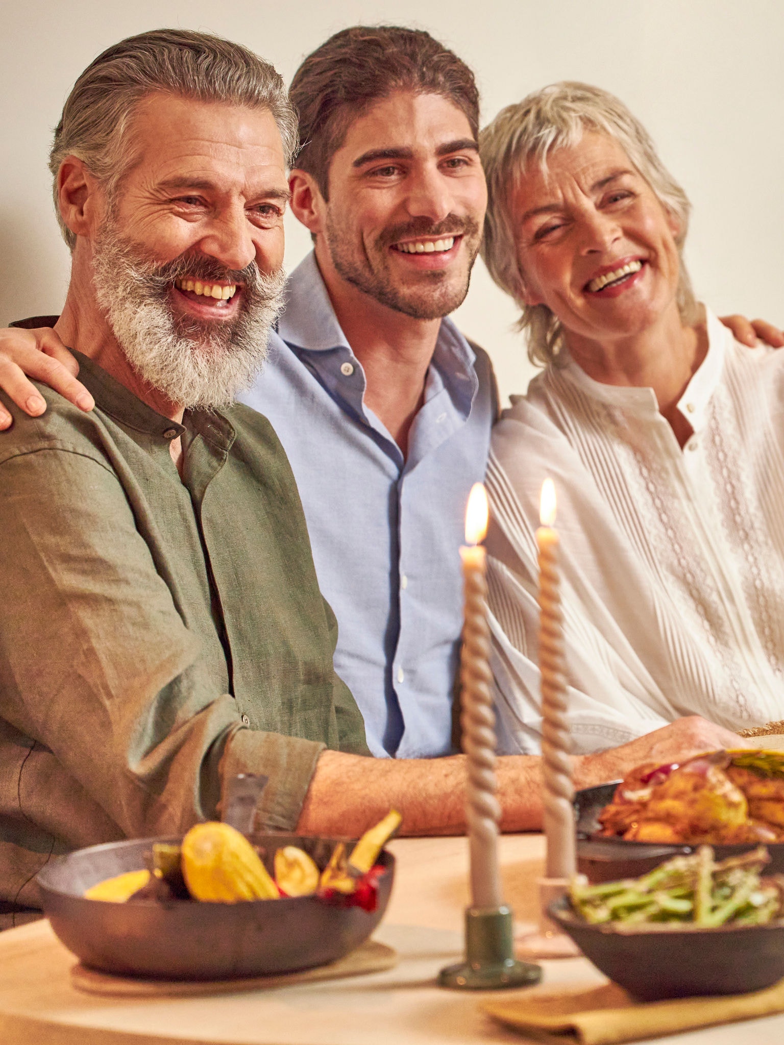 Hijo adulto con sus padres felizmente sentados a la mesa
