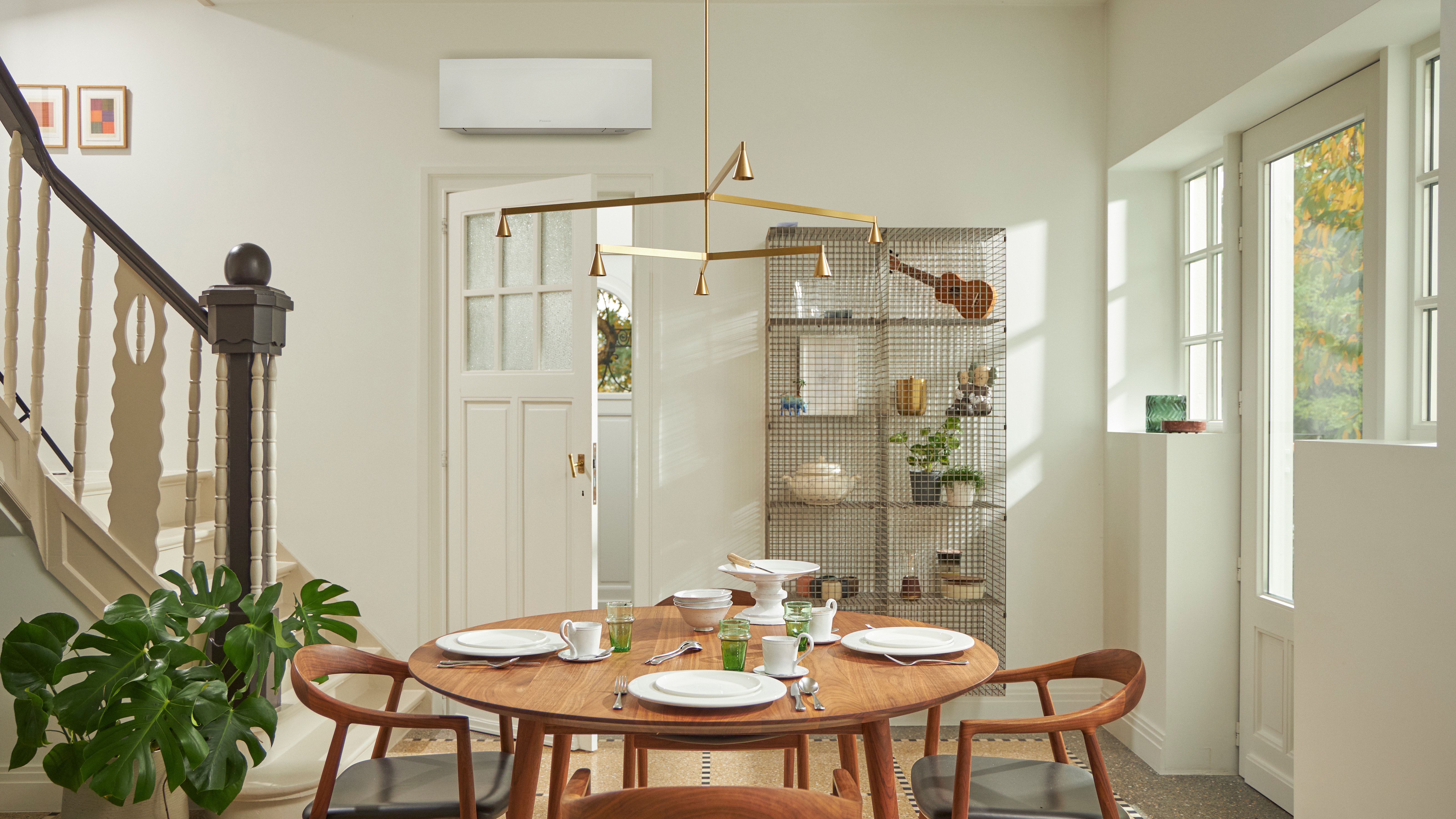 Habitación con una ventana grande, mesa de madera y un climatizador negro de pared.