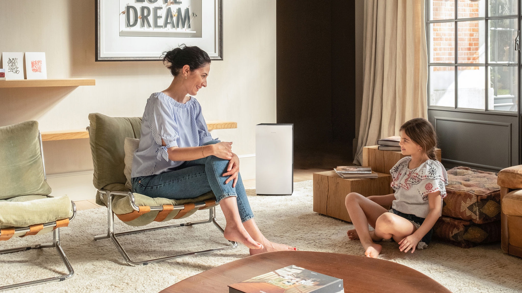 Mother talking happily to her little daughter in the living room that has clean air thanks to a Daikin air purifier